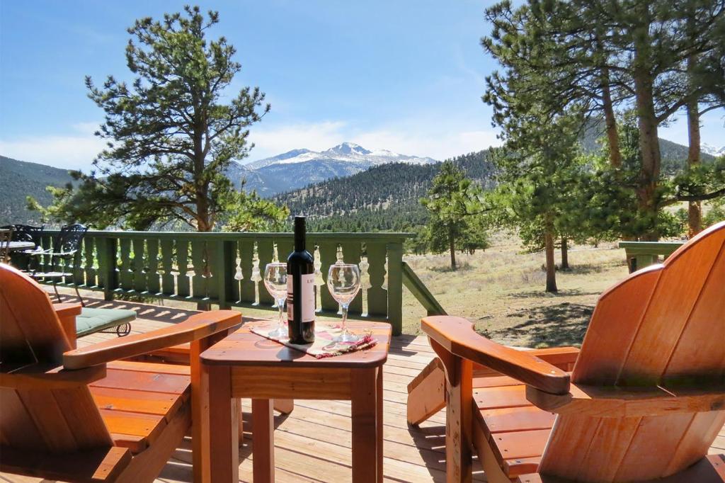 una mesa con una botella de vino y 2 sillas en una terraza en Longs Peak Lookout Cabin, en Estes Park