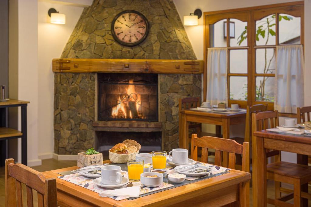 een eetkamer met een open haard en een tafel met eten bij Hotel Intermonti in San Martín de los Andes