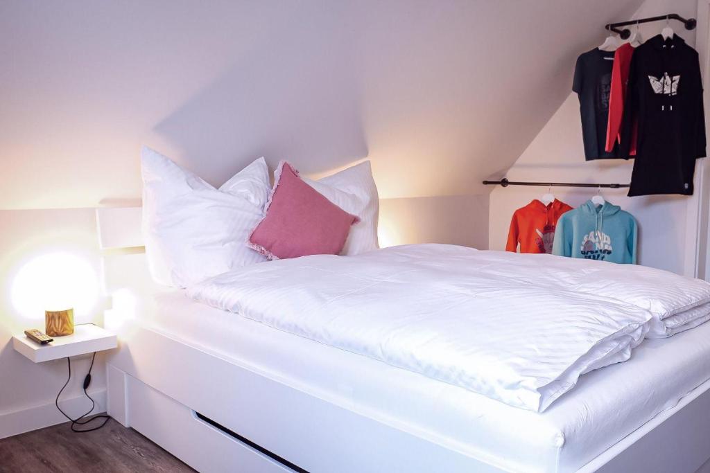uma cama com lençóis brancos e almofadas cor-de-rosa num quarto em Flippi-s-Hues-SUeD em Westerland