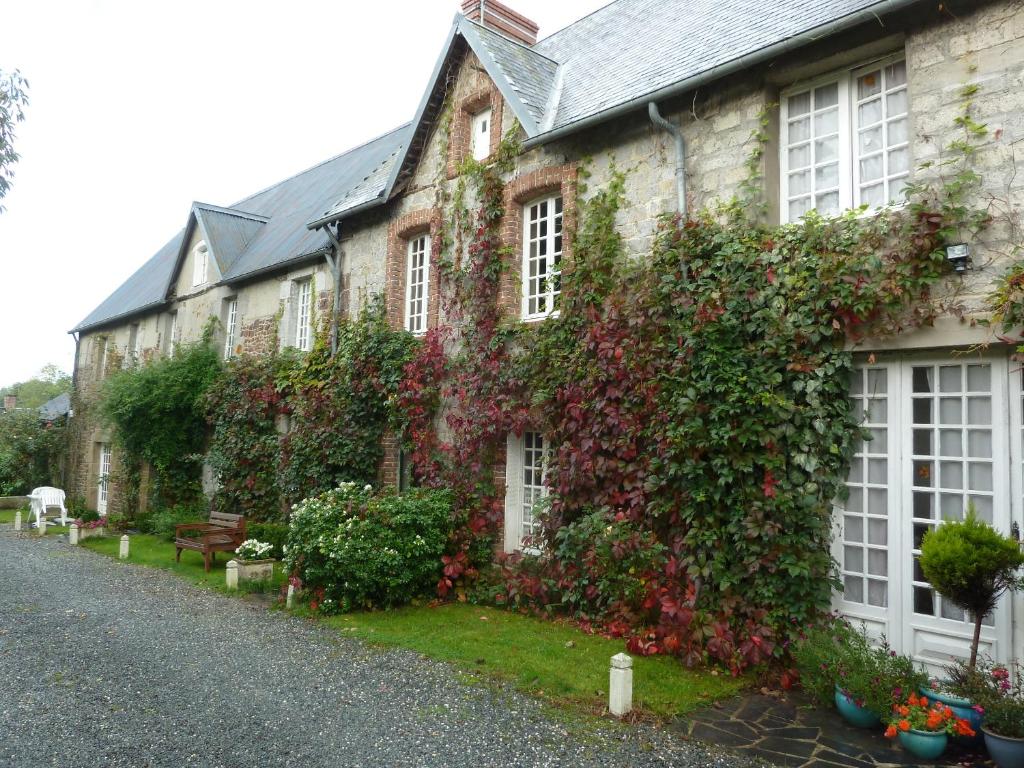 un bâtiment recouvert de lierre et de fleurs à côté d'une rue dans l'établissement La Verte Campagne - 50660 Trelly, à Trelly