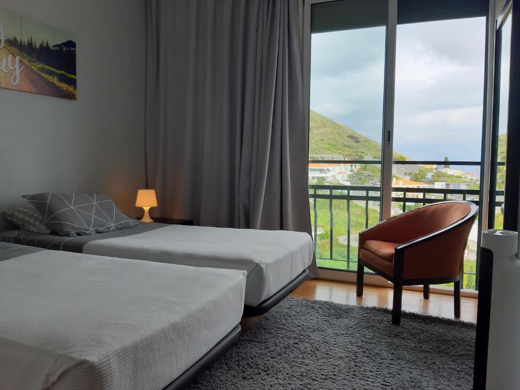 a bedroom with two beds and a chair and a window at Apartamentos América - Blue Sea in Funchal