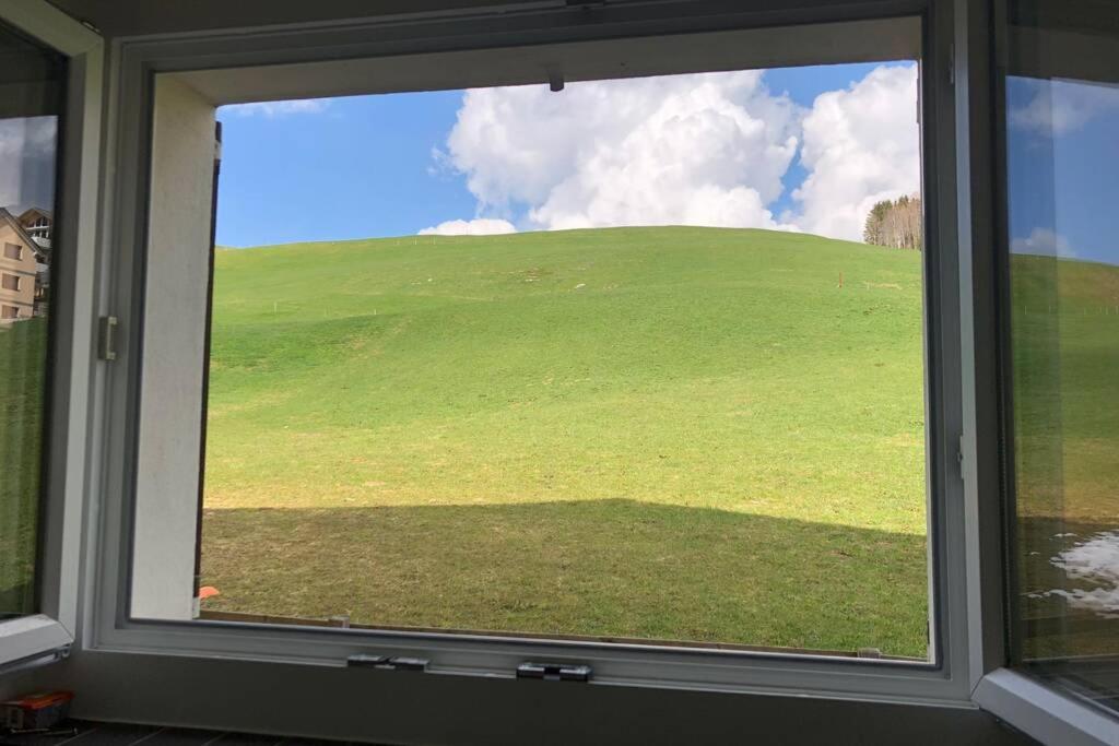 a view of a green hill through a window at Gemütliche Unterkunft in den Bergen in Oberiberg
