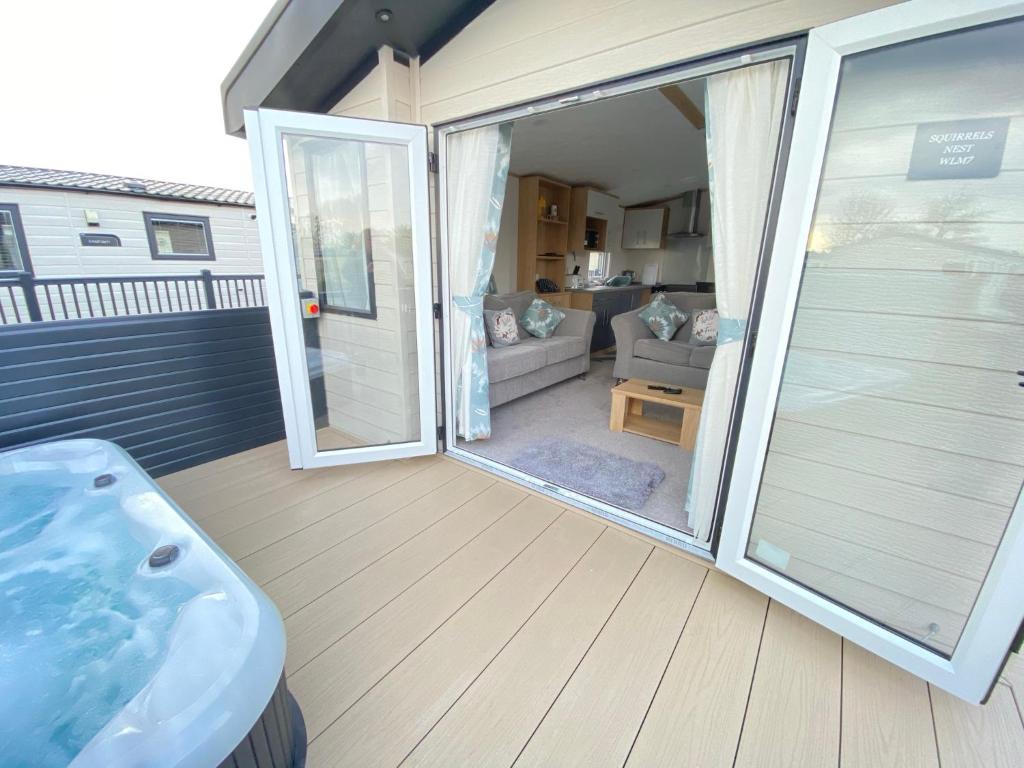 una puerta corredera de cristal abierta que da a un patio con sofá en Waggy Tails - Hot Tub - Pet Friendly, en South Cerney