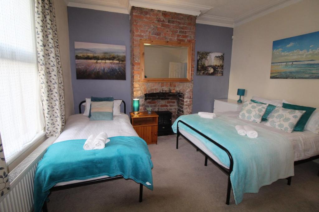 two beds in a room with a fireplace at Somerset House in Sheffield
