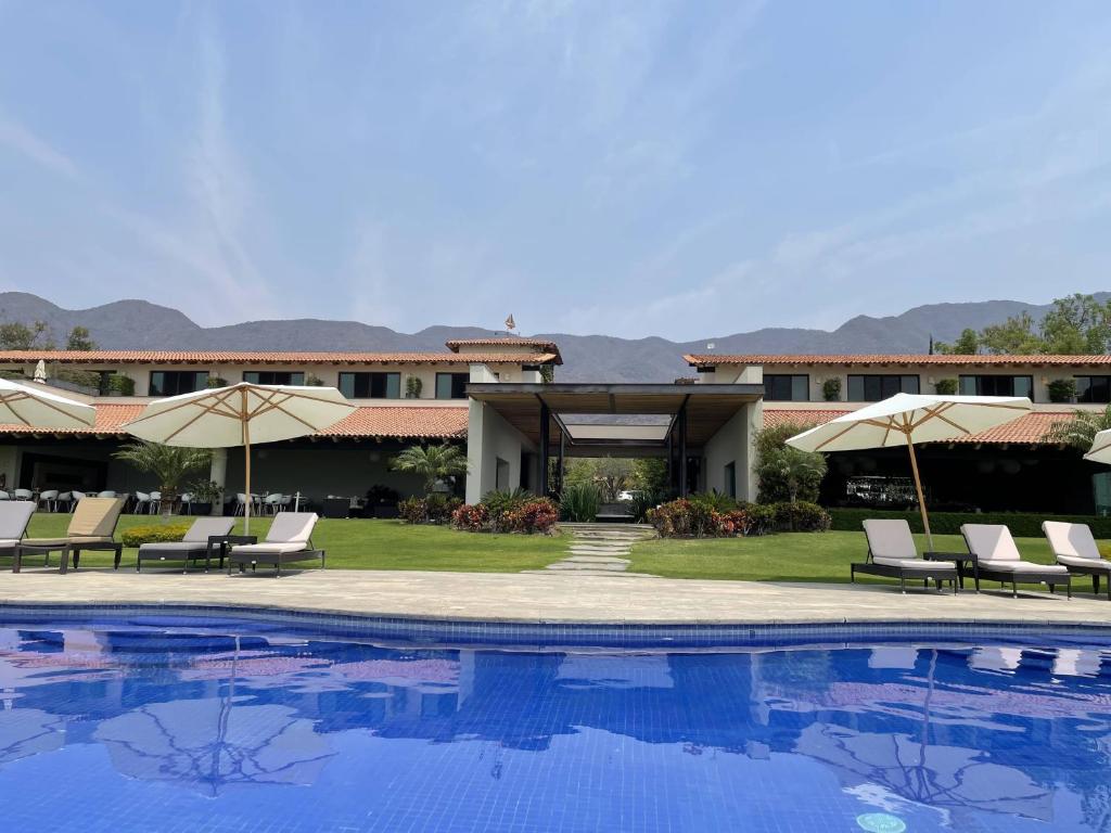 a resort with a swimming pool with chairs and umbrellas at La Reserva Chapala in Ajijic