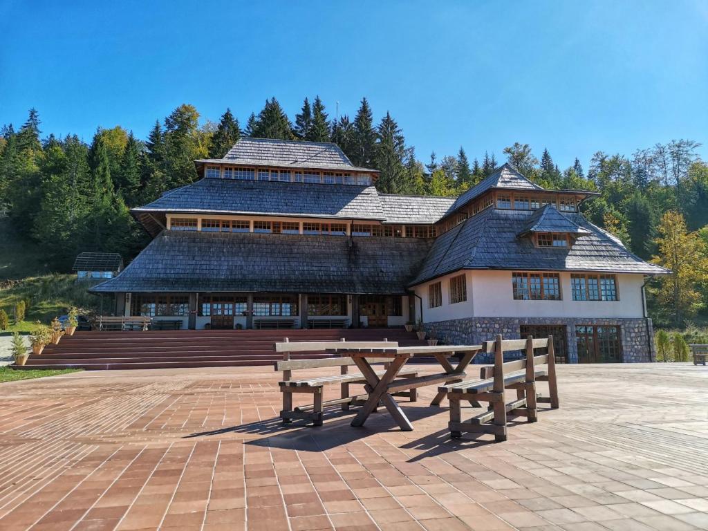 a building with two wooden benches in front of it at Čarobni Breg in Mokra Gora