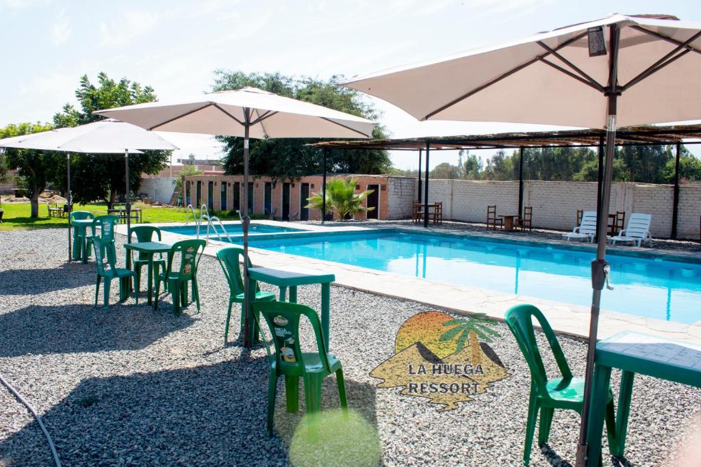 - une piscine avec des tables, des chaises et des parasols dans l'établissement Hospedaje La Huega, à Ica