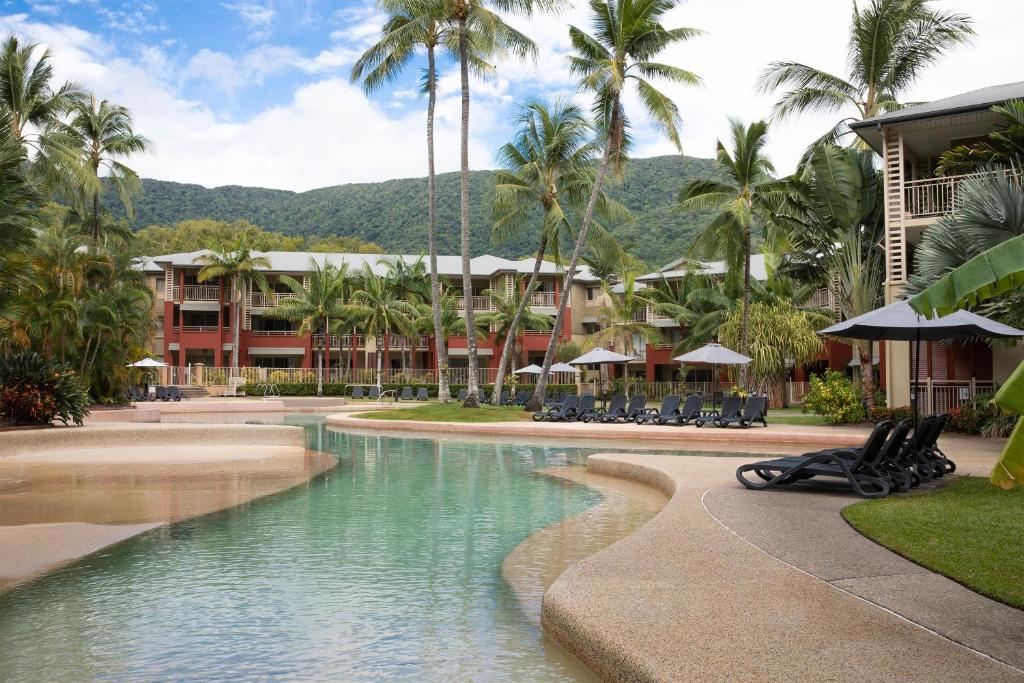 a resort swimming pool with palm trees and a resort at Mantra Amphora in Palm Cove