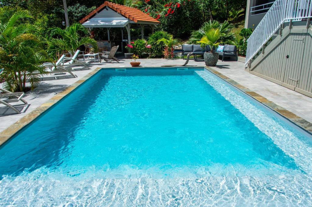 a swimming pool with blue water in a yard at Kaz O'Rocher - Sea View Appartements in Le Diamant