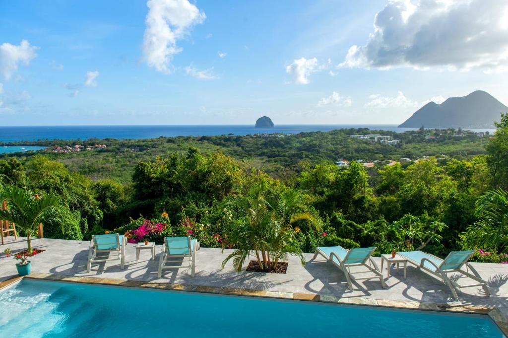 a resort pool with a view of the ocean at Kaz O'Rocher - Sea View Appartements in Le Diamant