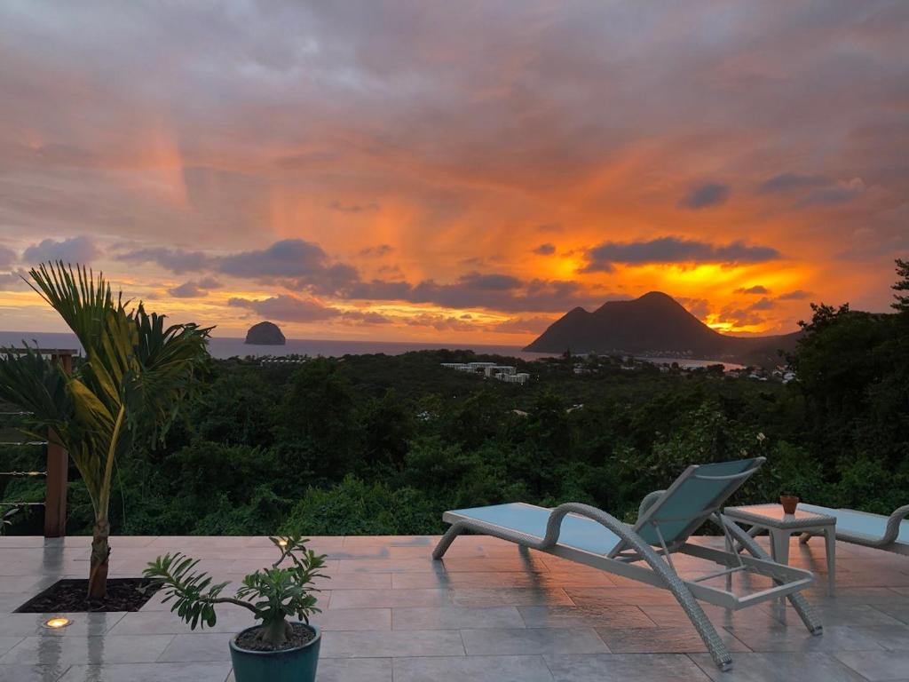 a chair sitting on a patio with a sunset at Kaz O'Rocher - Sea View Appartements in Le Diamant