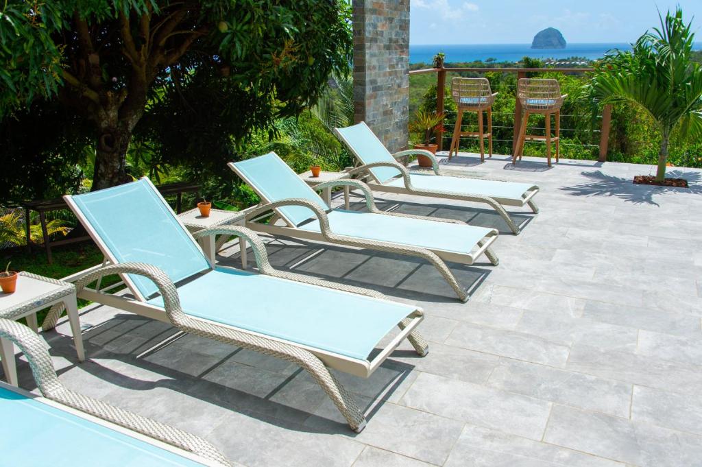 a group of chairs and tables on a patio at Kaz O'Rocher - Sea View Appartements in Le Diamant