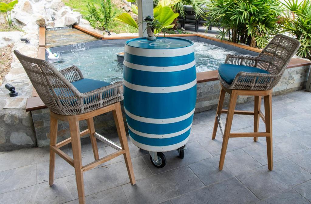 a barrel sitting between two chairs next to a swimming pool at Kaz O'Rocher - Sea View Appartements in Le Diamant