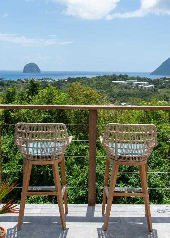 two chairs sitting on a balcony looking out at the ocean at Kaz O'Rocher - Sea View Appartements in Le Diamant
