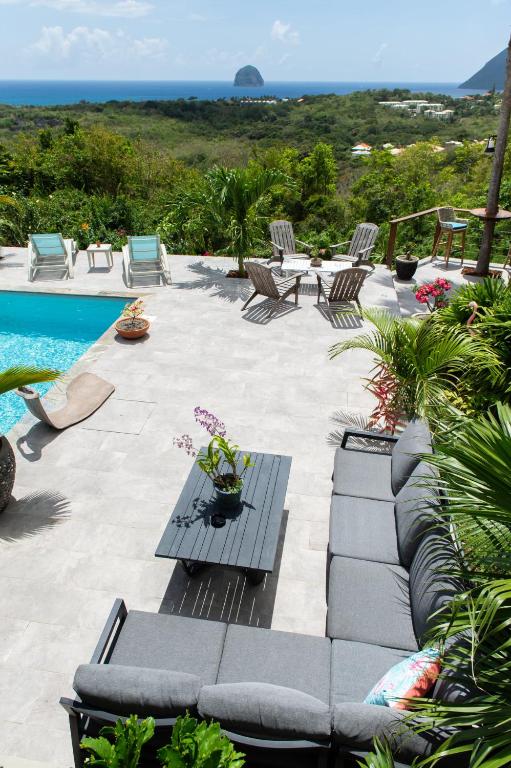 a patio with chairs and a table and a pool at Kaz O'Rocher - Sea View Appartements in Le Diamant