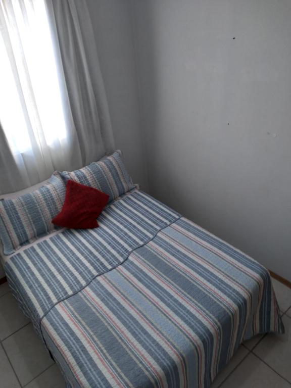 a bed with a red pillow on it in a room at apartamento com piscina in Piçarras