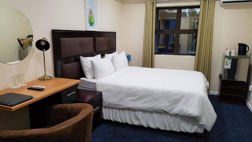 Johannesburg的住宿－Garden Top Hotel，酒店客房配有一张床、一张桌子和一把椅子。