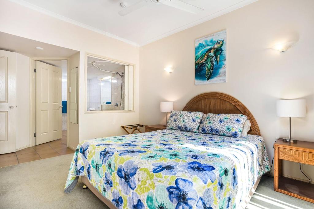 1 dormitorio con 1 cama con colcha azul y amarilla en A Taste of the Tropics, en Cairns