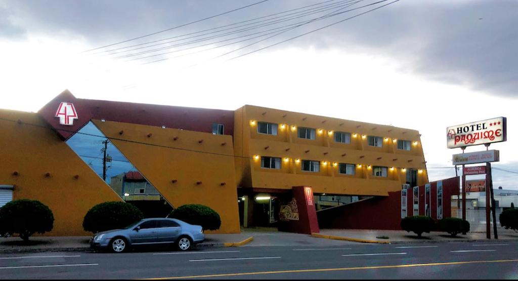 une voiture garée devant un bâtiment jaune dans l'établissement Hotel Paquime, à Nuevo Casas Grandes