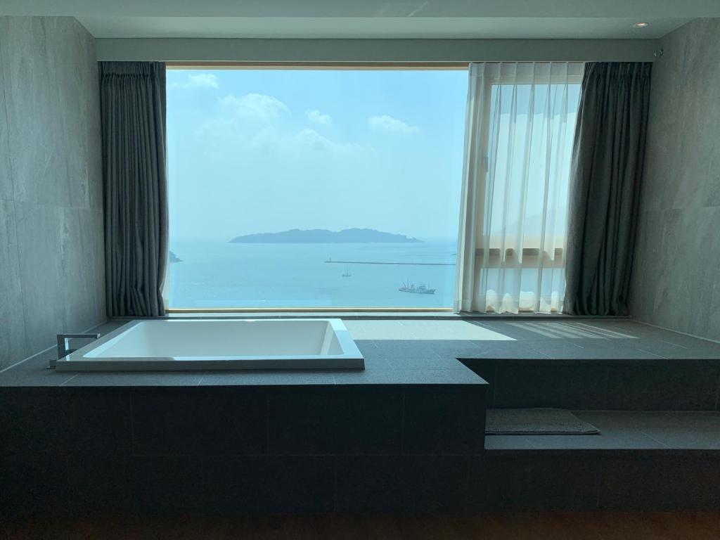 巨济Hotel SANG SANG & Private SANG SANG POOL VILLA的一间位于大窗户前的带浴缸的浴室
