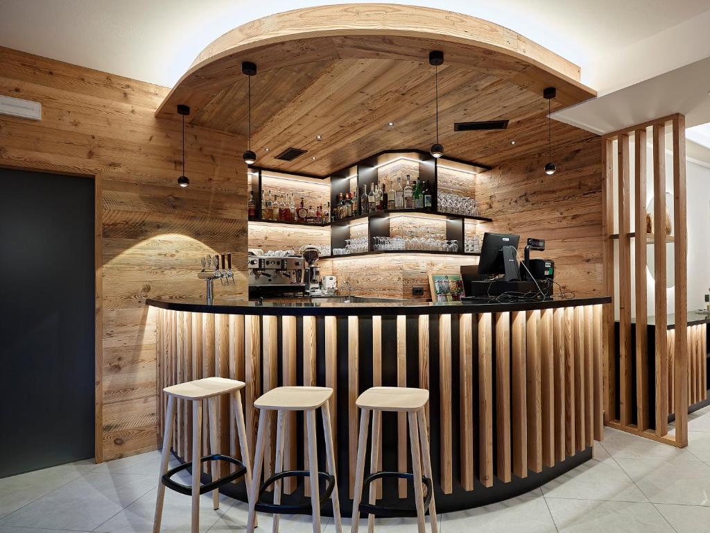 a bar in a restaurant with wooden walls and stools at Albergo Maggiorina in Ledro