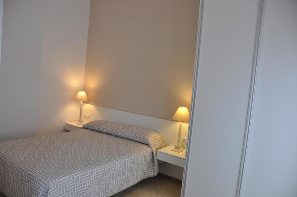 バレンシアにあるValencia City Center New Apartmentsの小さなベッドルーム(ベッド1台、ランプ2つ付)