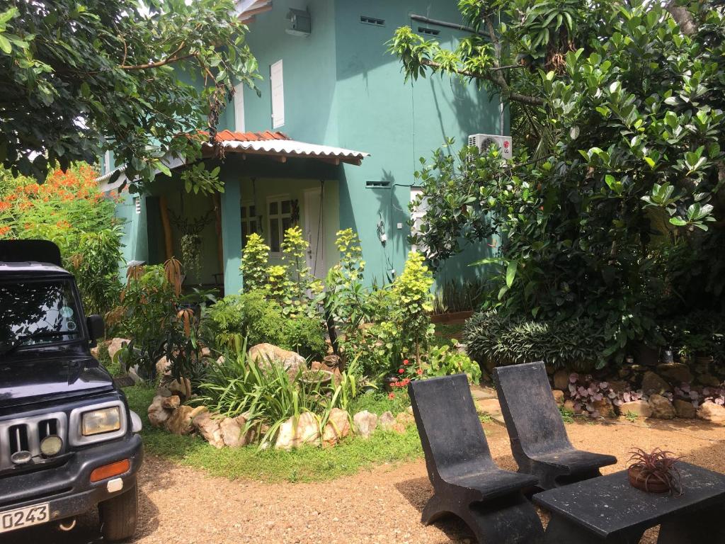 dos sillas negras sentadas frente a una casa azul en Owl's Nest Chalet, en Udawalawe