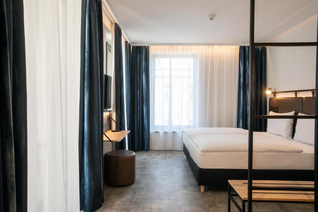 a hotel room with two beds and a large window at H2 Hotel Budapest in Budapest