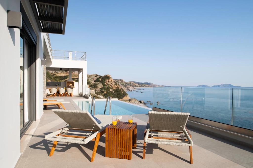 patio z 2 krzesłami i stołem oraz widokiem na ocean w obiekcie Rozites Luxury Beachfront Villa w mieście Kerames