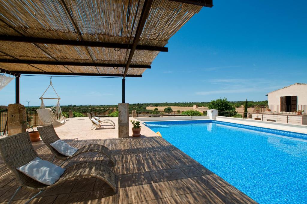 a swimming pool with two chairs and a umbrella at Finca Can Carro in Campos
