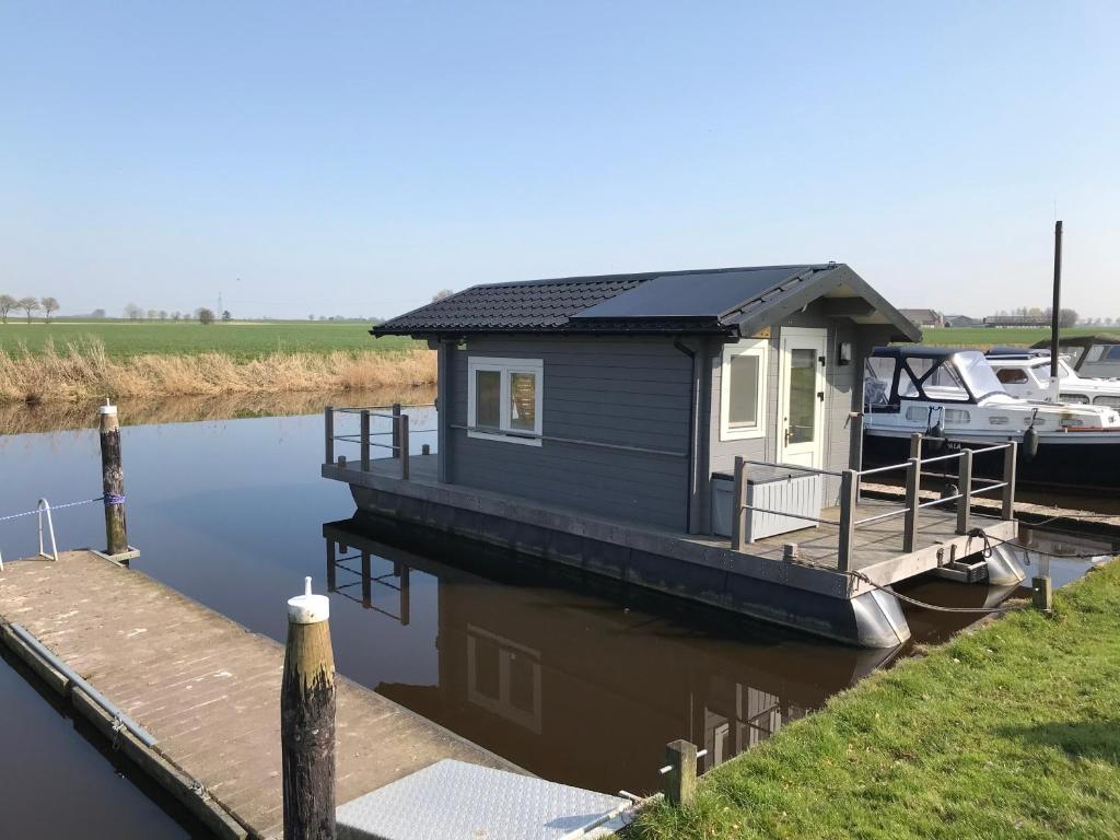 a small house on a dock next to a boat at Waterhut 2 Aduarderzijl in Feerwerd
