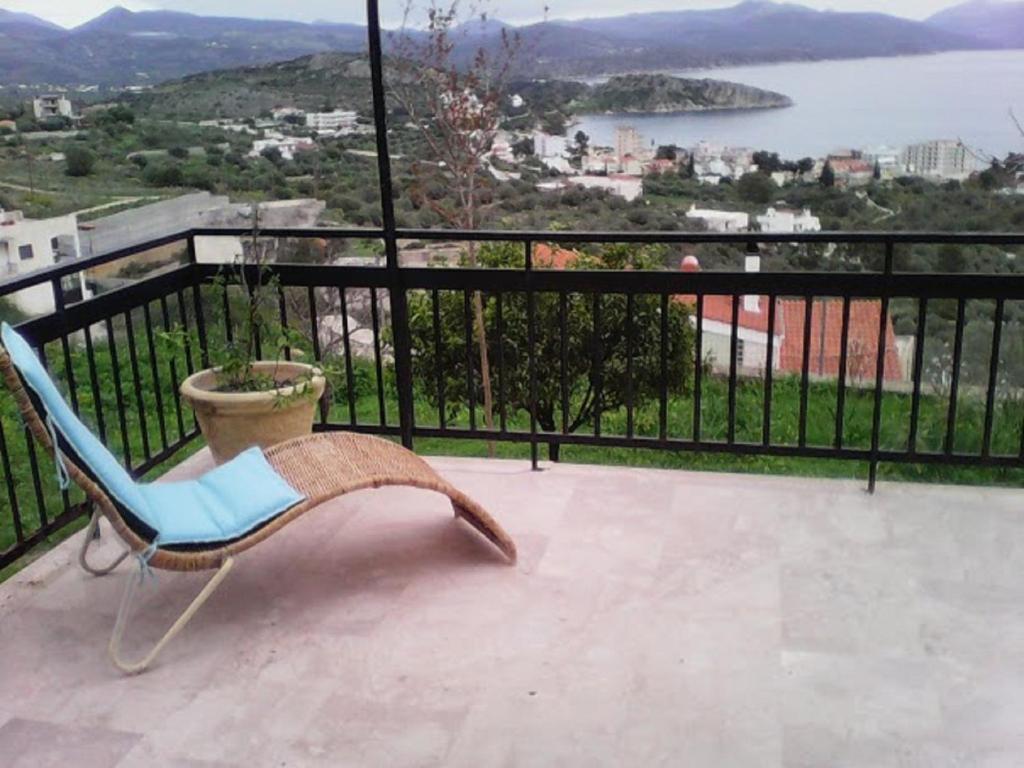 a chair on a balcony with a view of the water at Aperando in Tolo