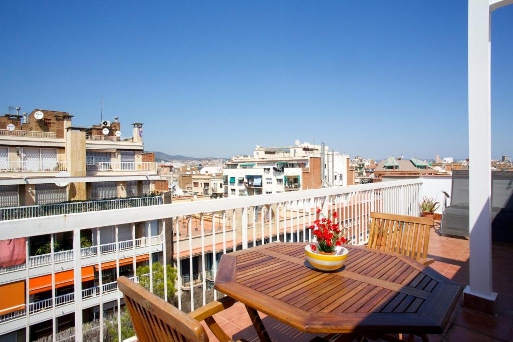 a wooden table on a balcony with a view of a city at Attic Bcn Central Terrace in Barcelona