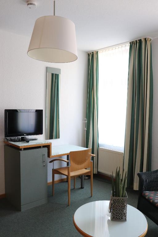 uma sala de estar com uma mesa e uma televisão em Gästehaus Germania em Wangerooge