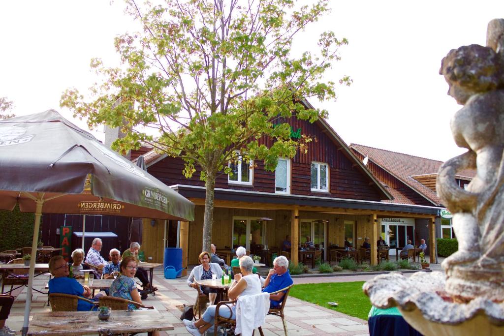 un groupe de personnes assises à des tables devant un bâtiment dans l'établissement Hotel De Kruishoeve 's-Hertogenbosch - Vught, à Vught