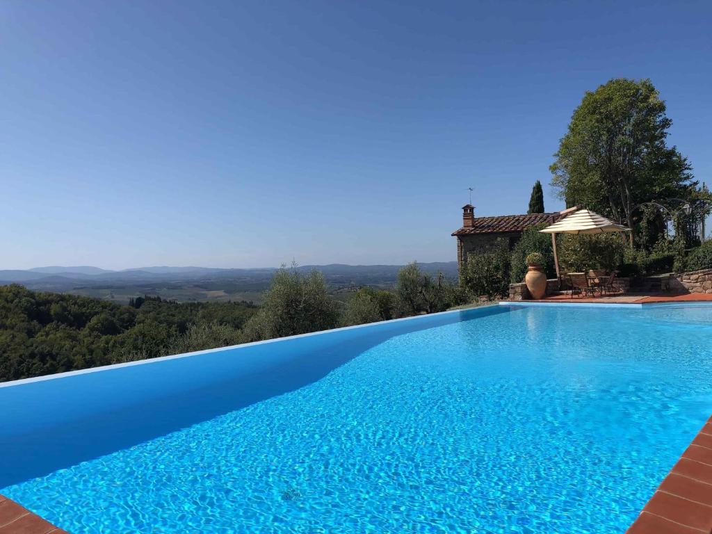 einen Pool mit Blick auf ein Haus in der Unterkunft Cipressini in Castellina in Chianti