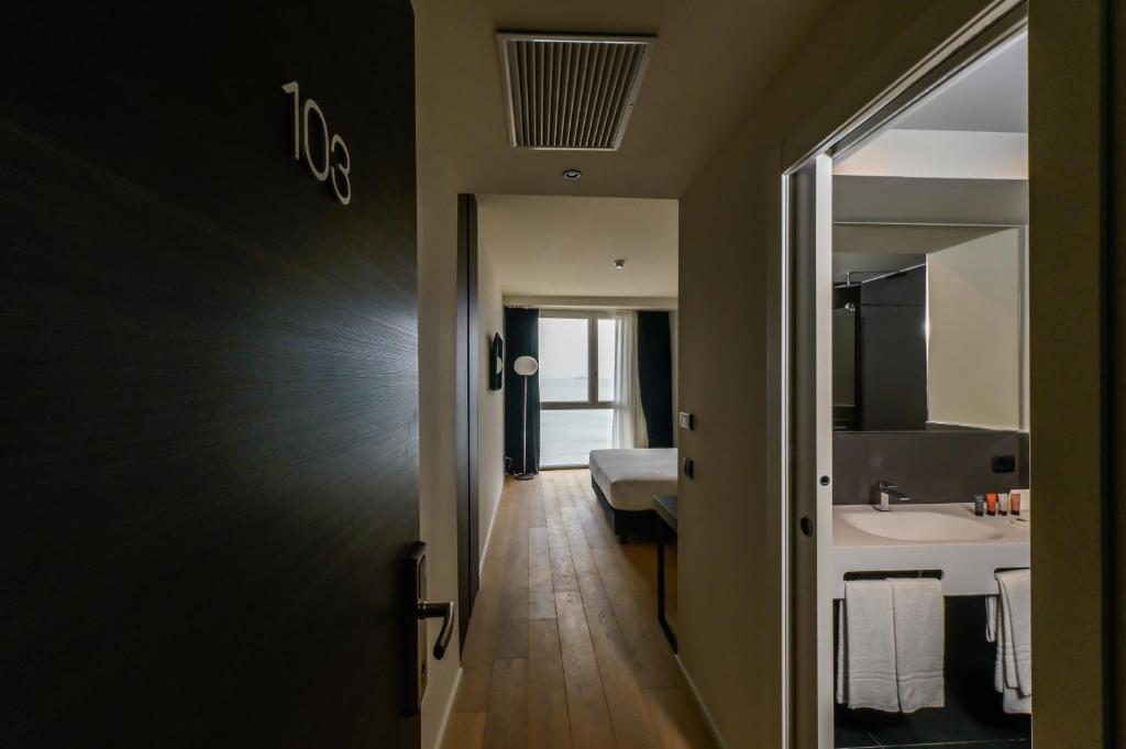 a hallway leading to a bathroom with a sink and a bed at Hotel Punta Tipa in Trapani