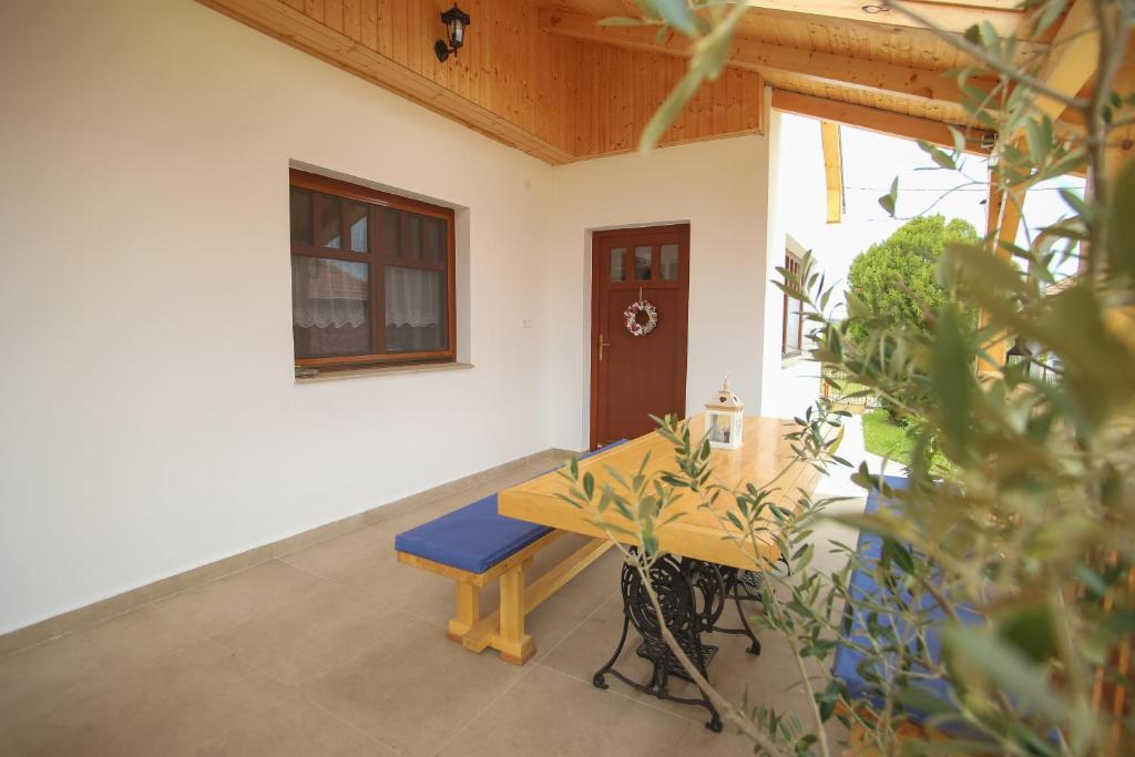 a porch with a wooden table and a bench at Rózsa Vendégház in Polány