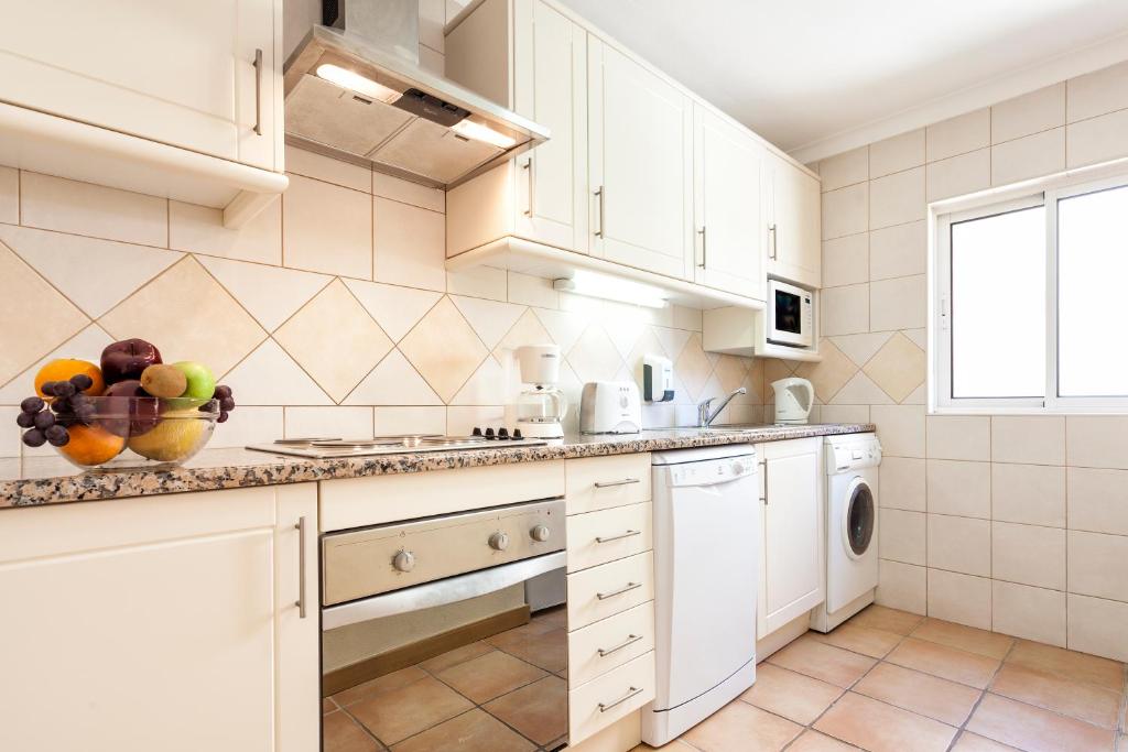 a kitchen with white cabinets and a bowl of fruit on the counter at Pestana Palm Gardens in Carvoeiro
