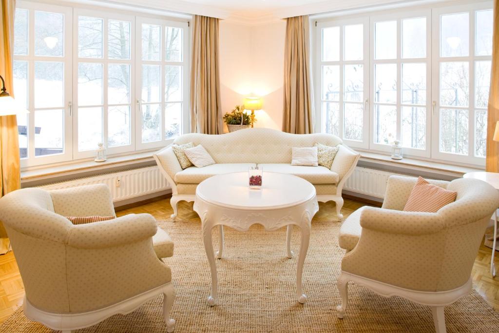 ein Wohnzimmer mit Sofas, einem Tisch und Stühlen in der Unterkunft Romantik Hotel Landhaus Bärenmühle in Frankenau