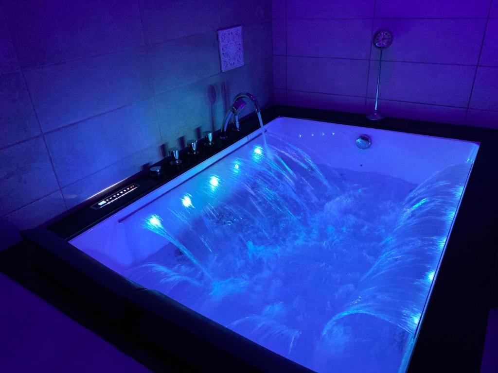 Una gran bañera en una habitación con luces. en Suite Darcy & Spa, en Dijon