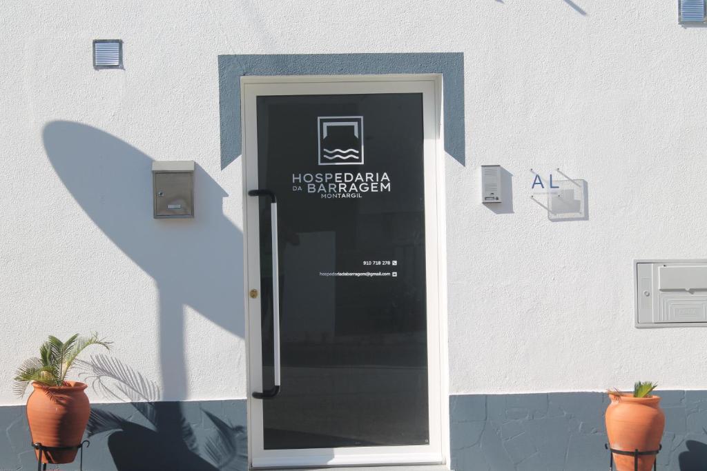 een deur met een bord aan de zijkant van een gebouw bij Hospedaria Da Barragem in Montargil