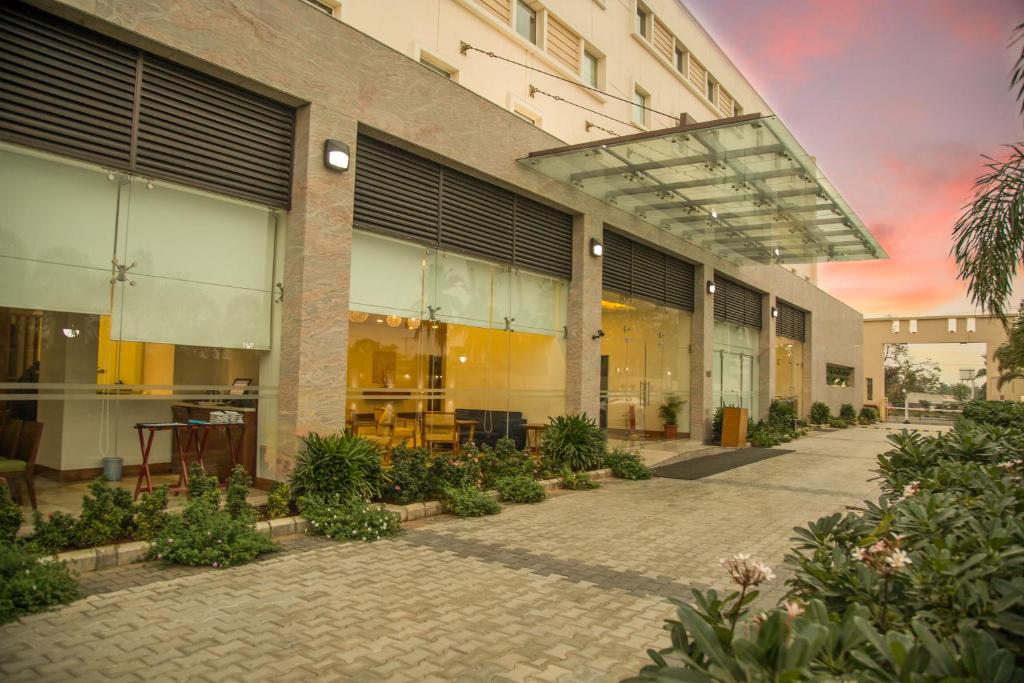 Kalyan Grand - a business hotel في Vandalūr: مبنى به ساحة مع طاولات ونباتات