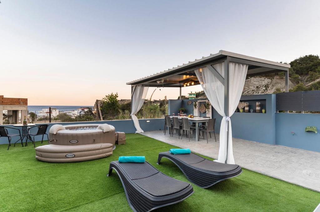 a patio with a canopy and chairs and grass at Royal Luxury Studios in Archangelos