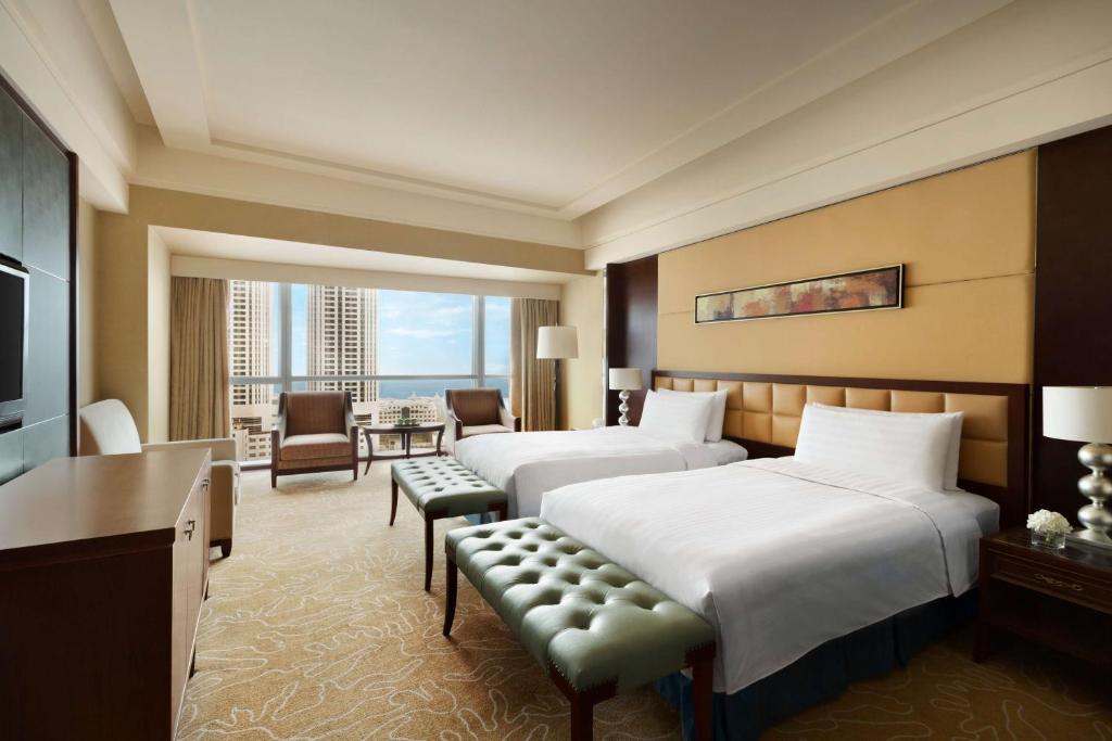 a hotel room with two beds and a desk at Shangri-La Qingdao in Qingdao