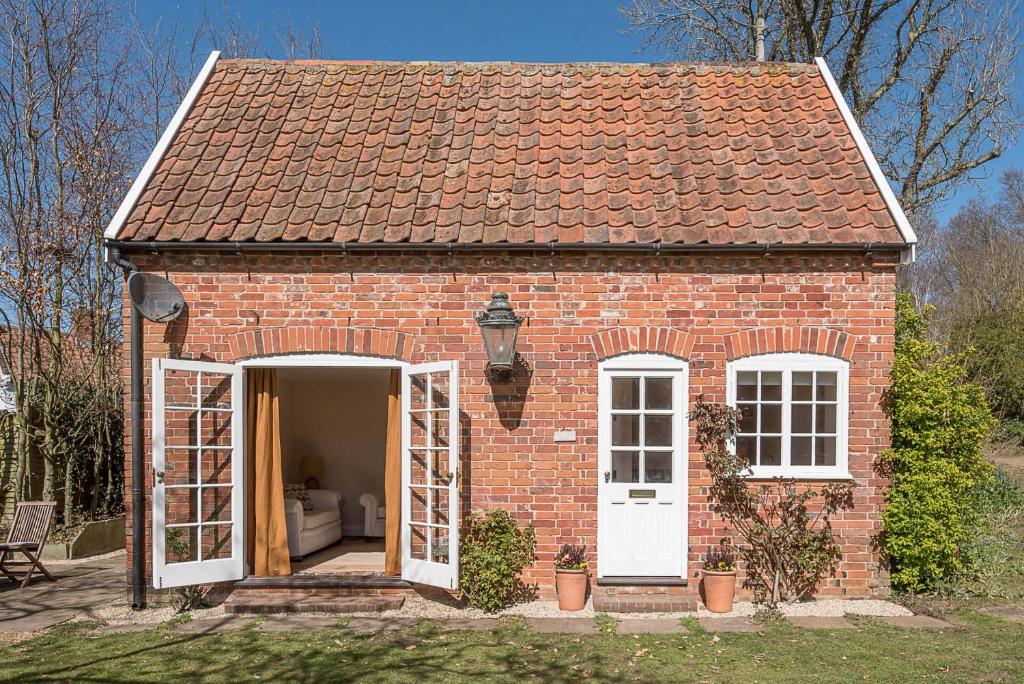 a red brick house with a white door and windows at The Coach House Eyke Air Manage Suffolk in Woodbridge