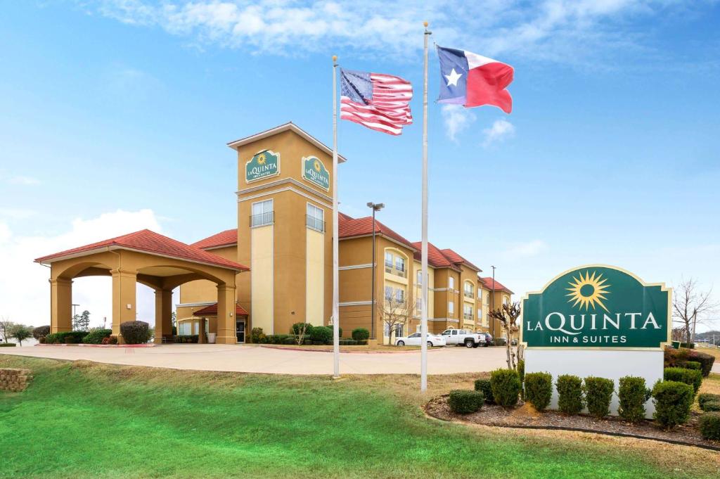 een hotel met twee vlaggen voor een gebouw bij La Quinta by Wyndham Longview North in Longview