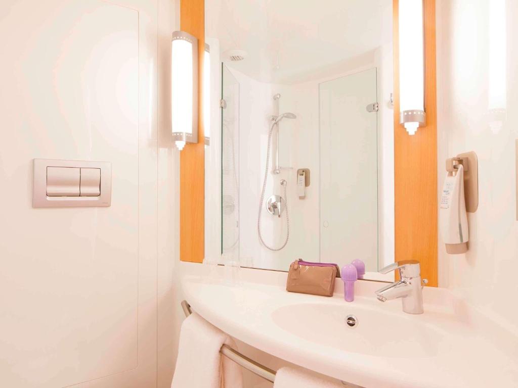 a white bathroom with a sink and a mirror at ibis London Elstree Borehamwood in Borehamwood
