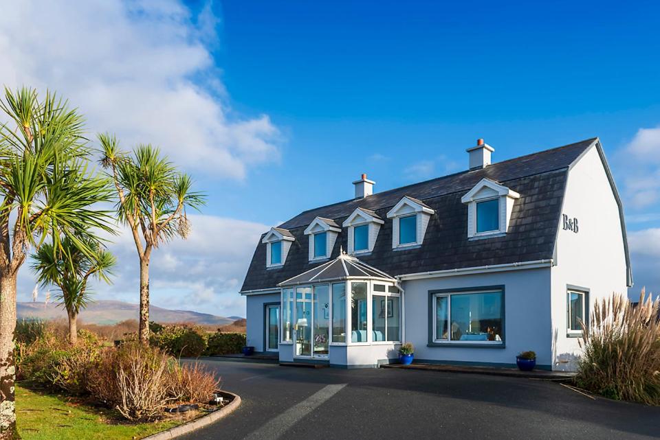 a white house with a black roof and palm trees at Klondyke House B&B in Waterville
