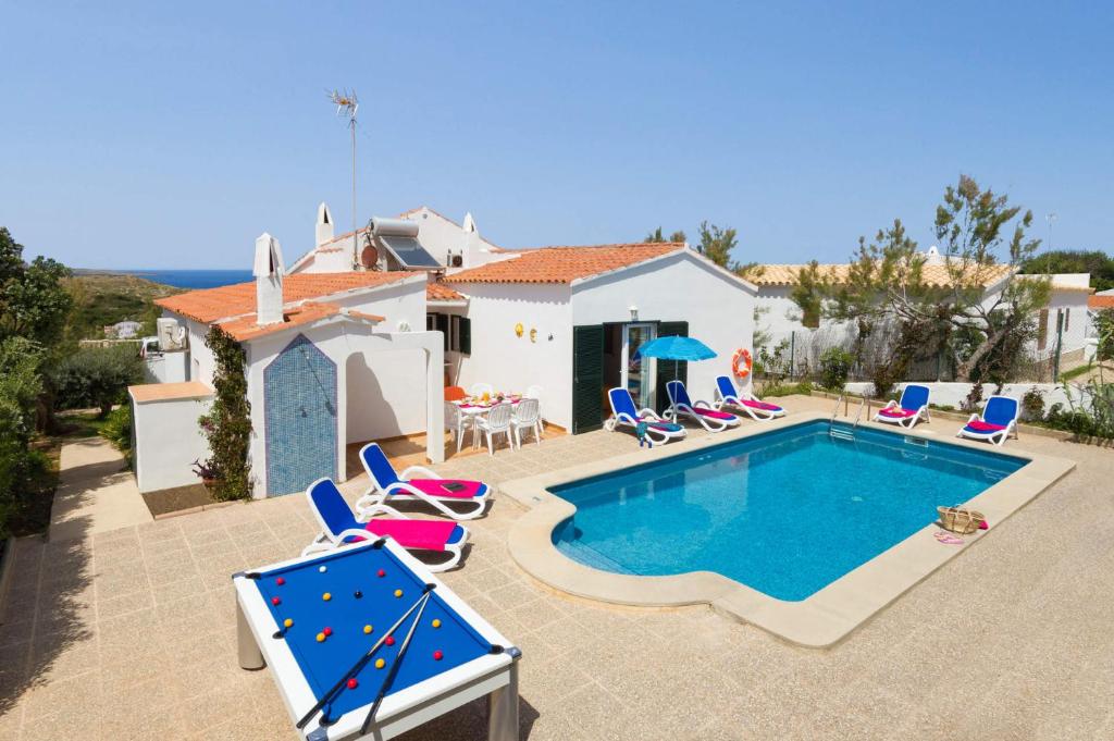 een villa met een zwembad en stoelen en een huis bij Villa Romani by Villa Plus in Arenal d'en Castell